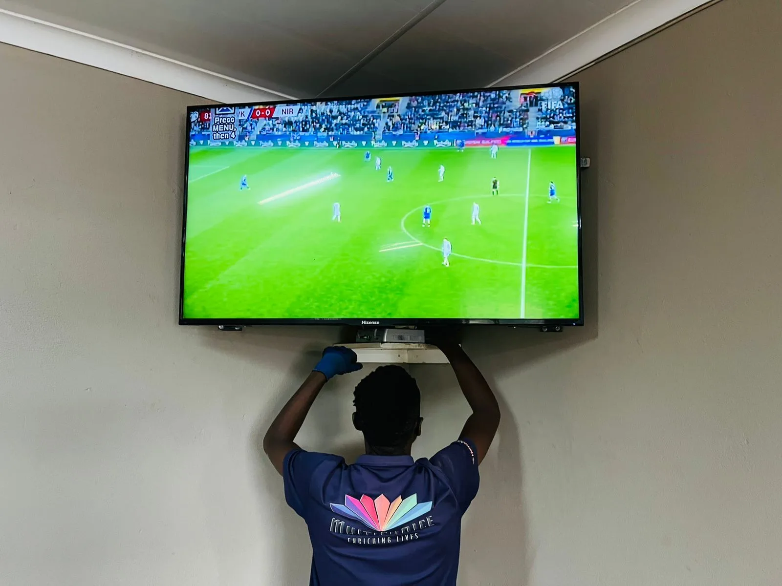 MultiChoice-uniformed technician fitting a TV wall bracket for a DSTV installation